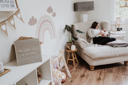 Eine Frau sitzt im Sessel mit einem Baby.