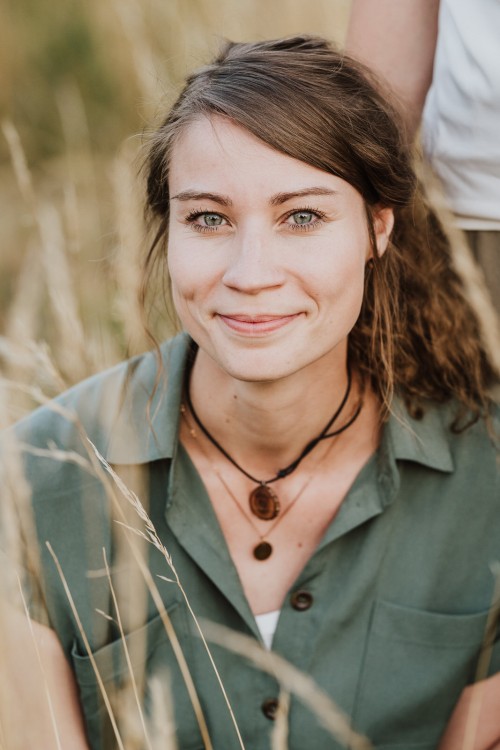 Eine Frau sitzt auf einer Wiese.