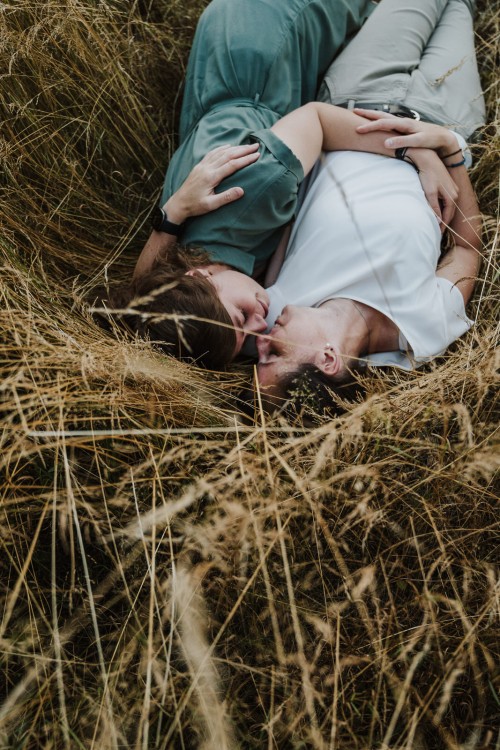 Zwei Frauen liegen im hohen Gras und kuscheln.