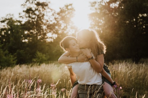 Eine Frau nimmt eine zweite Frau huckepack.