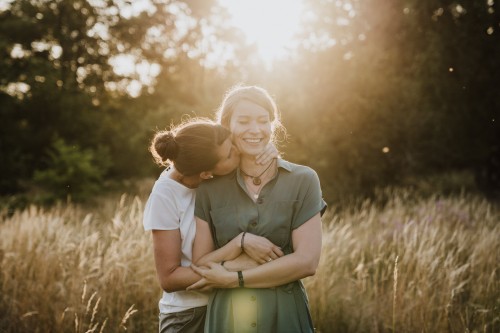 Eine Frau küsst eine andere Frau am Hals.