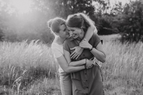 Zwei Frauen kuscheln mitten auf einer Wiese.