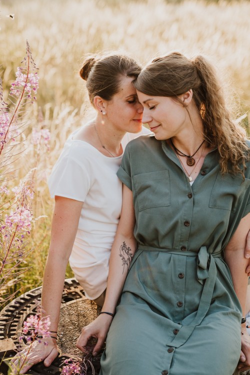 Zwei Frauen kuscheln sitzend mitten auf der Wiese.