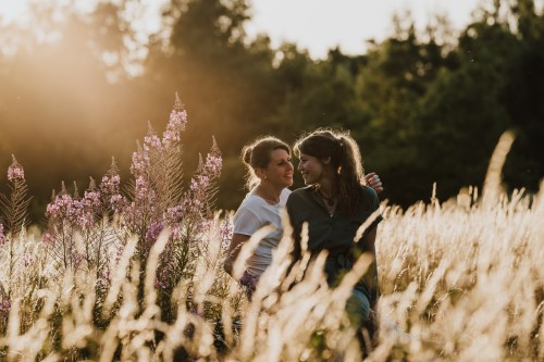 Zwei Frauen sitzen zwischen den Blumen auf einer Wiese.