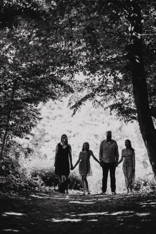Ein Mann, eine Frau und zwei Mädchen spazieren durch einen Wald.