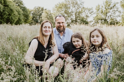 Eine Frau, ein Mann und zwei junge Mädchen sitzen auf einer Wiese,