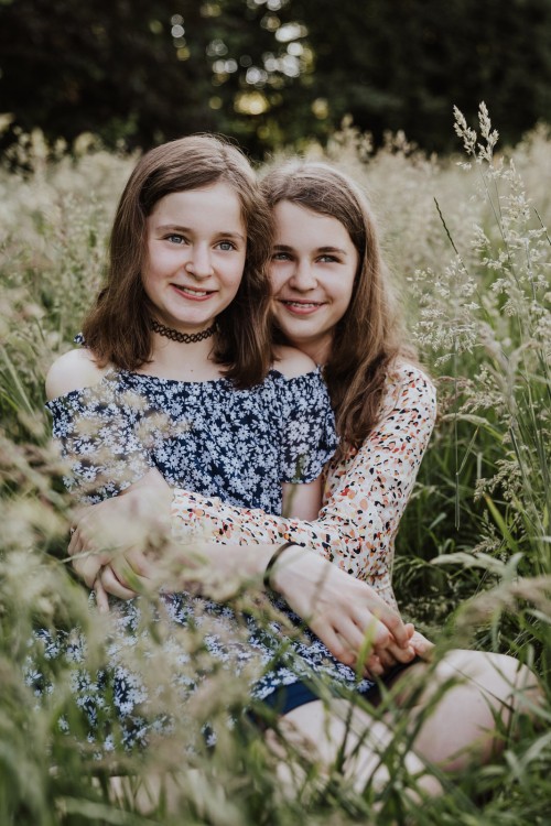 Zwei Mädels sitzen auf einer Wiese.
