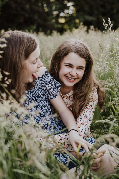 Zwei Mädels sitzen auf einer Wiese.