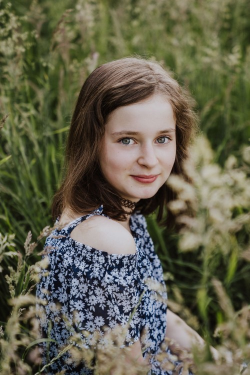 Ein junges Mädchen sitzt auf einer Wiese.