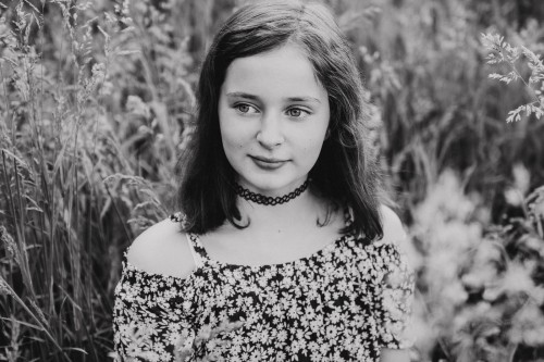 Ein Mädchen sitzt auf einer Wiese.