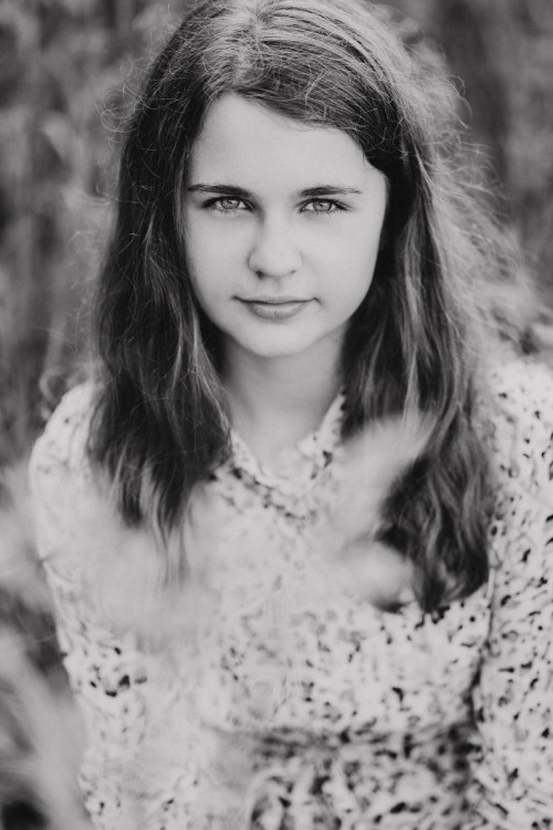 Ein Mädchen sitzt auf einer Wiese.