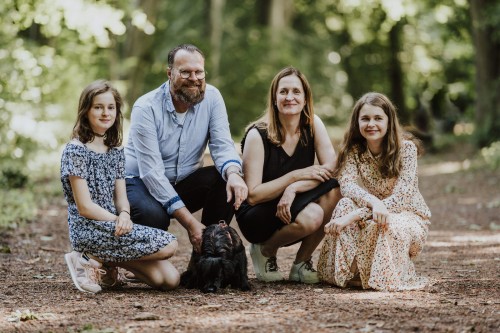 Ein Mann, eine Frau und zwei Mädchen hocken im Wald.