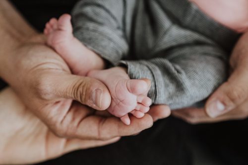 Ein Mann hält Babyfüße in seiner Hand.