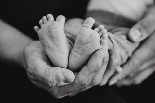 Ein Mann hält Babyfüße in seiner Hand.