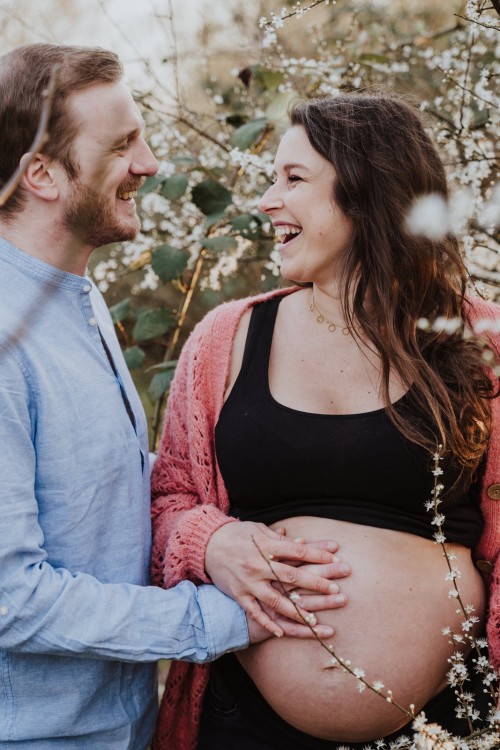 Ein Mann und eine Frau halten die Hände auf dem Schwangerschaftsbauch.