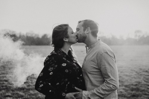 Eine Frau und ein Mann küssen sich mitten auf einem Feld.