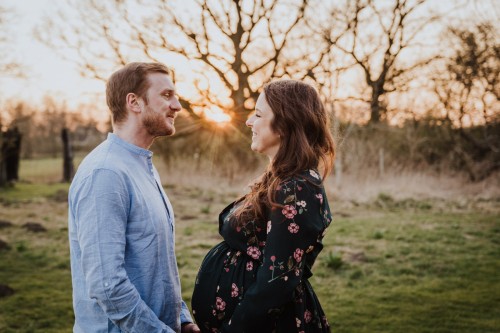 Eine schwangere Frau und ein Mann mitten auf einem Feld.