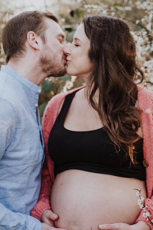 Ein Mann küsst eine schwangere Frau.