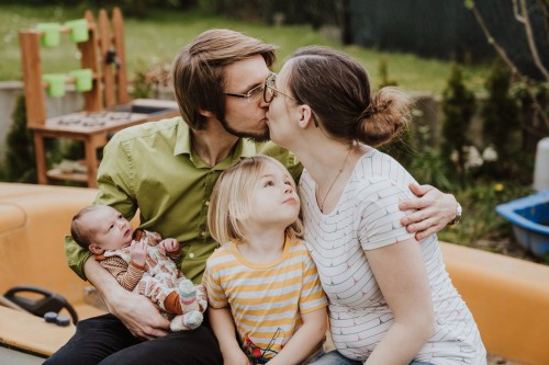 Ein Mann und eine Frau küssen sich und die zwei Kinder schauen zu.