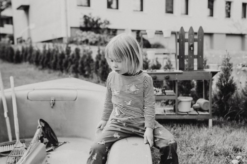 Ein Kind sitzt auf einer Bank im Garten.