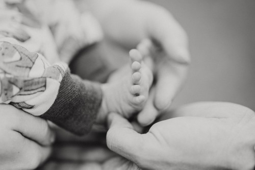 Kleine Baby Füße werden von großen Händen gehalten.