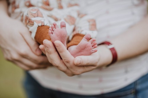 Kleine Baby Füße werden von einer Frau in den Händen gehalten.