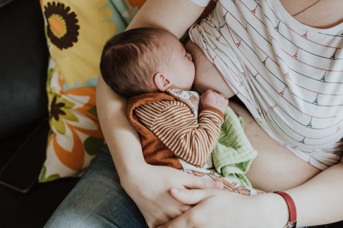 Ein neugeborenes Baby wird von einer Frau gestillt.