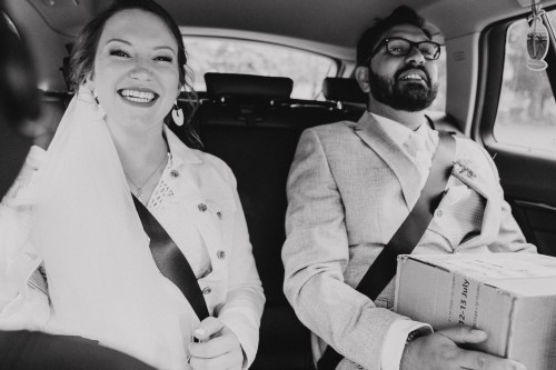 Ein schwarz-weißes Foto vom Brautpaar wie die im Auto sitzen.