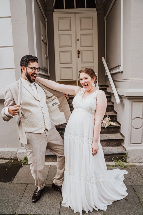 Ein Brautpaar tanzt fröhlich vor einer Treppe.