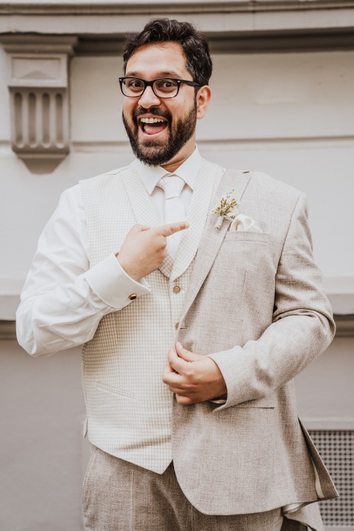 Ein Bräutigam zeigt mit seinem Finger auf seinen Blumenanstecker.