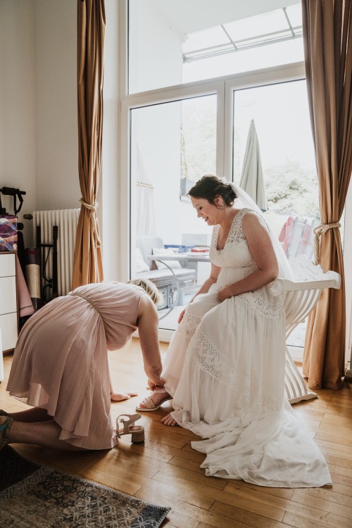 Eine Frau hilft einer Braut die Schuhe anzuziehen.