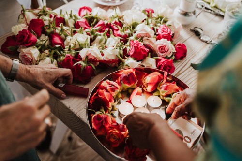 Ein Tisch mit einer Schale mit Blumen und Kerzen befüllt.