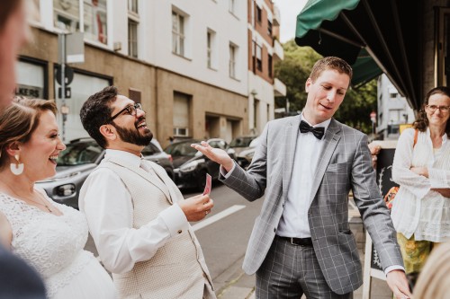 Ein Mann spricht mit einem Brautpaar auf der Straße.