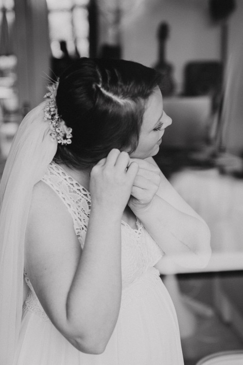 Eine Braut zieht ihr Ohrringe an.