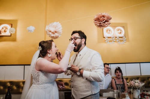 Eine Braut und ein Bräutigam füttern sich gegenseitig mit Kuchen.