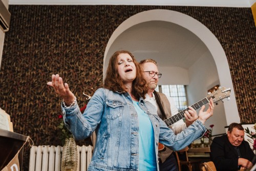 Eine Frau singt und ein Mann hinter ihr spielt Gitarre.