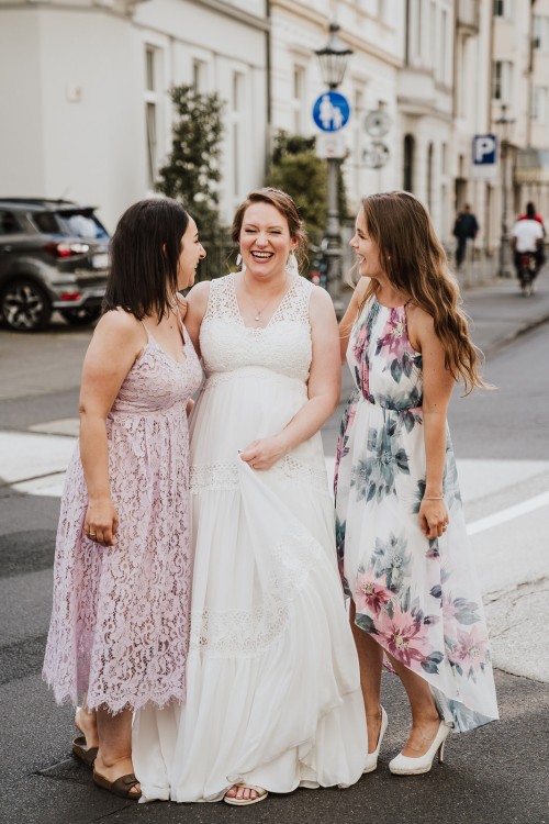Drei Frauen stehen auf der Straße und lachen.