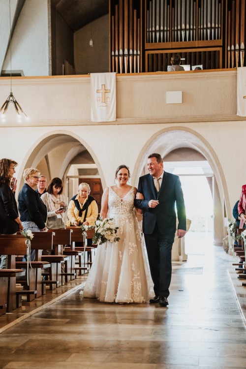 Eine Braut geht mit einem Mann durch eine Kirche.