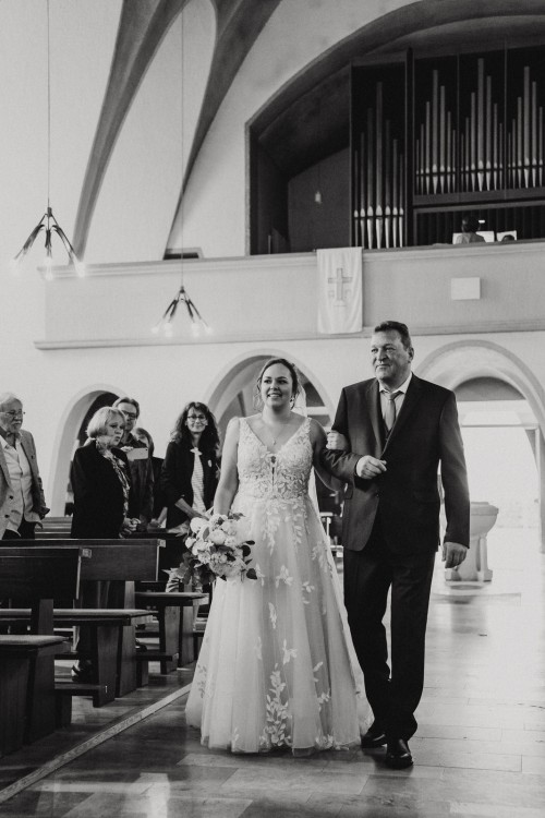 Eine Braut geht mit einem Mann durch eine Kirche.
