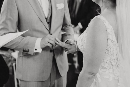 Ein Bräutigam steckt einer Braut einen Ring an.