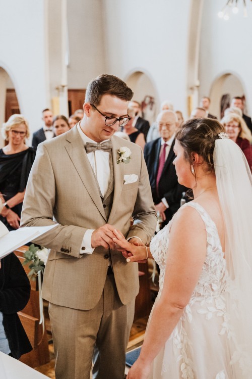 Ein Bräutigam steckt einer Braut einen Ring an.