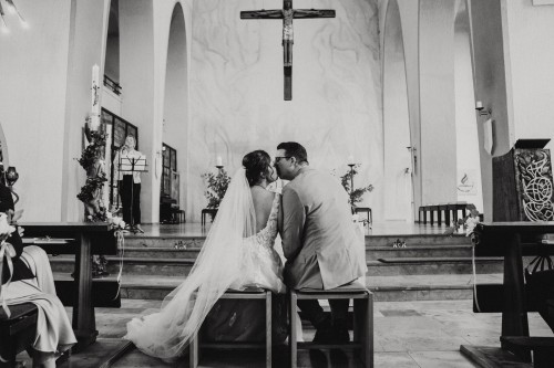Ein schwarz-weißes Bild vom Brautpaar dass sich in einer Kirche küsst.