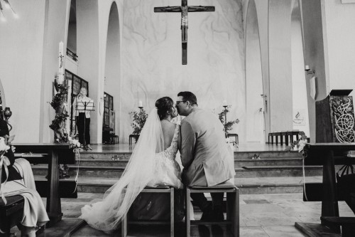 Ein schwarz-weißes Bild vom Brautpaar dass sich in einer Kirche küsst.