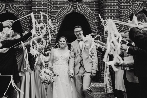 Ein schwarz-weißes Bild vom Brautpaar beim Auszug aus der Kirche.