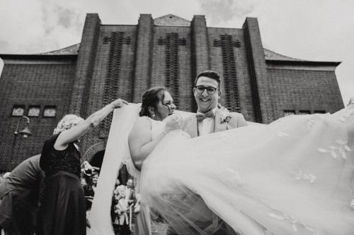 Ein Bräutigam trägt eine Braut auf den Händen.