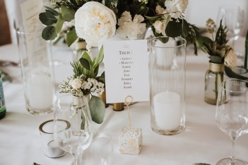 Blumen und eine Tischkarte mit Sitzordnung auf dem Tisch.