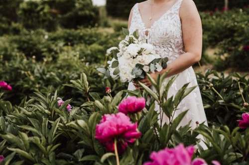 Eine Braut steht im Park zwischen den Blumen.