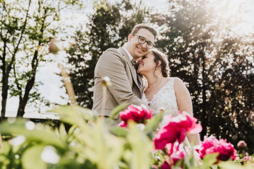 Eine Braut und ein Bräutigam stehen im Blumenfeld.