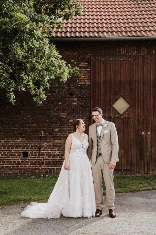 Eine Braut und ein Bräutigam stehen vor einer Scheune.
