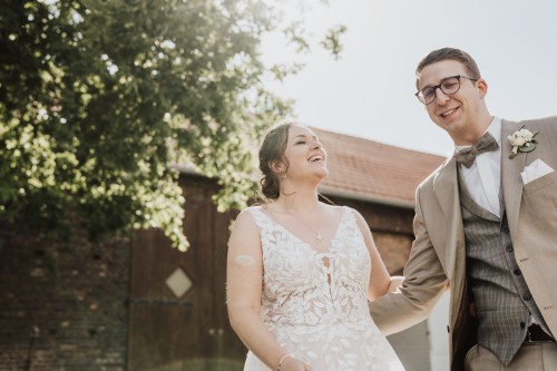 Eine Braut und ein Bräutigam stehen vor einer Scheune.